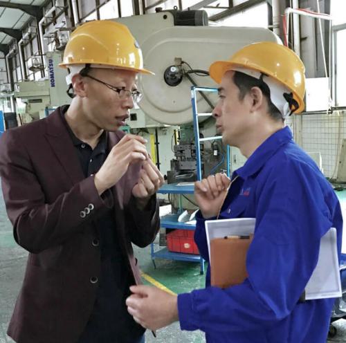 Mike (left) discusses a project's process with a factory representative.